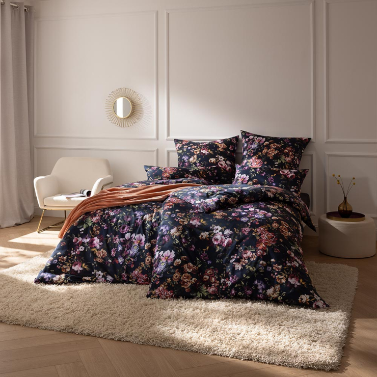 Bettwäsche Samuela mit Blumen in Rosa und Lila auf dunklem Grund auf Bett im Schlafzimmer