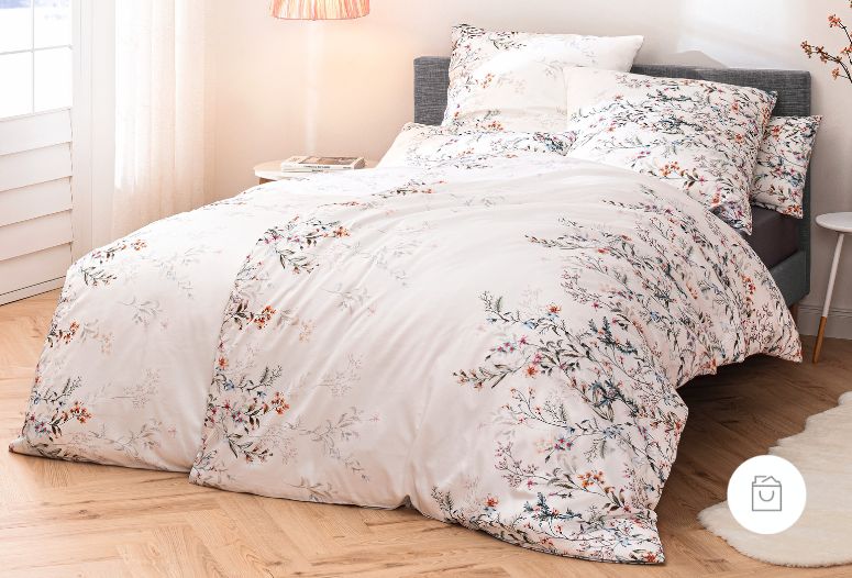 Satin de Luxe Bettwäsche mit feinem, floralen Muster in zarten Farben auf hellem, leicht glänzendem Stoff.