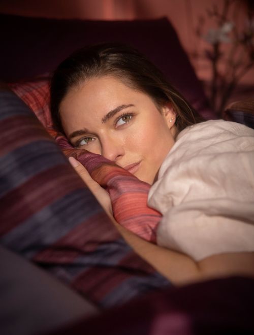 Nahaufnahme einer Frau die sich in die Bettwäsche Auri (demnächst lieferbar) kuschelt