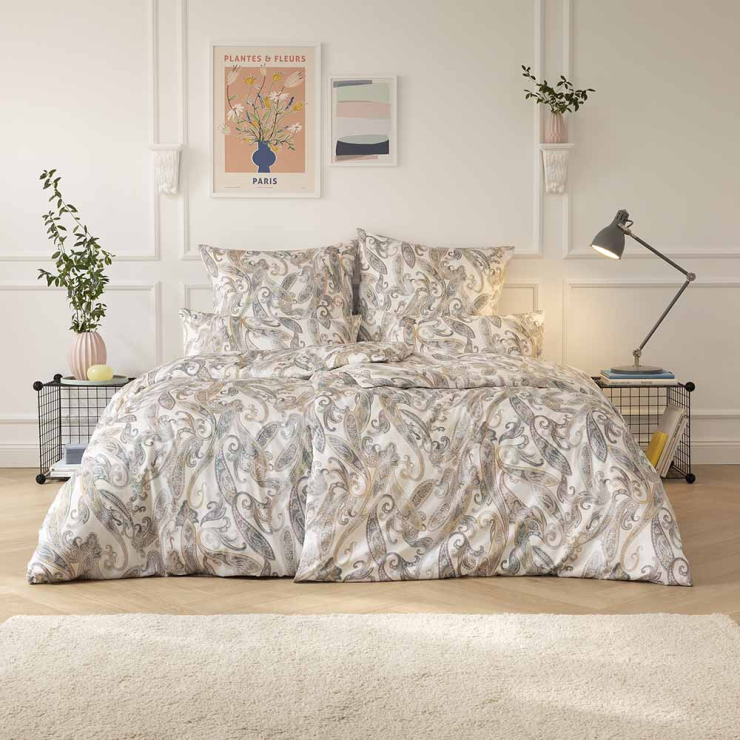 Bettwäsche Nexa mit Paisley-Muster in Beige und Grau auf hellem Grund auf Bett im Schlafzimmer