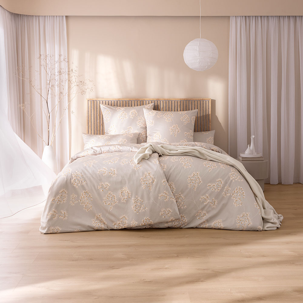 Bettwäsche Antje mit großem aber dezenten Blumenmuster in Beige und Weiß auf beigem Grund auf Bett im Schlafzimmer
