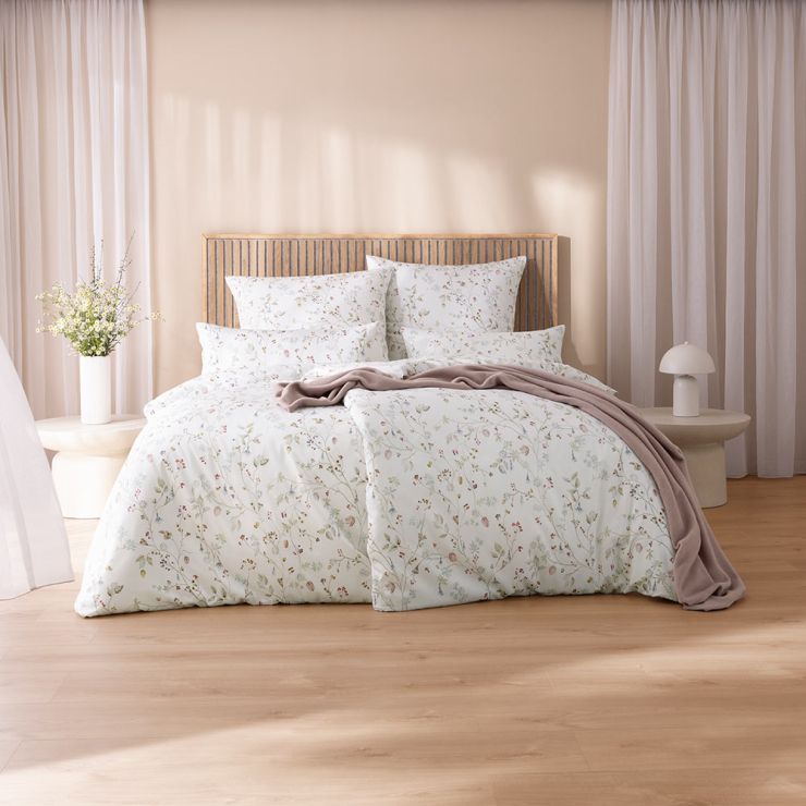 Bettwäsche Christa mit Blumenmuster in Rosa und Grün auf weißem Grund auf Bett im Schlafzimmer