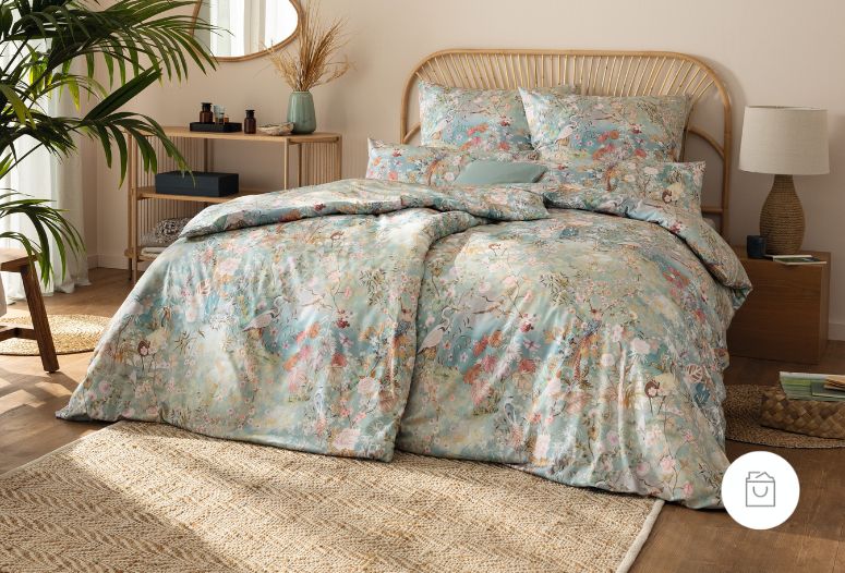 Bettwäsche Anthea mit großen Blüten und feinen Zweigen in Rosé-, Creme- und Grüntönen auf blaugrünem Grund auf Bett im Schlafzimmer