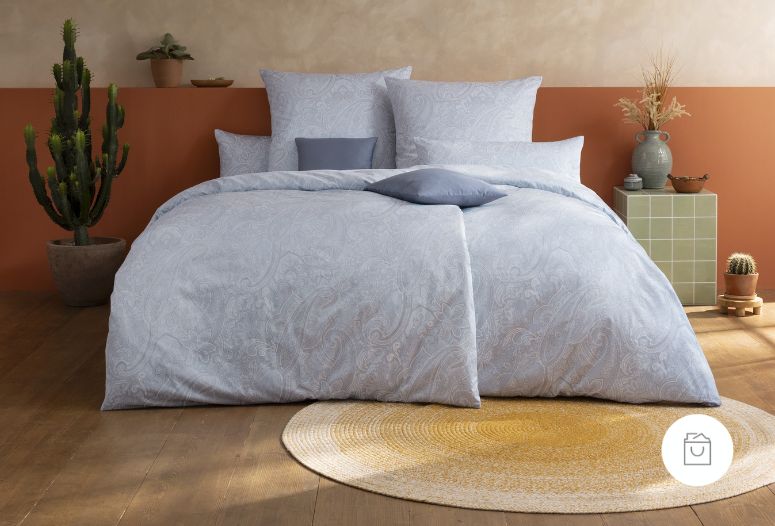 Bettwäsche Judith mit feinem Paisley-Muster aus geschwungenen Ornamenten in kühlen Blau- und Grautönen auf Bett im Schlafzimmer