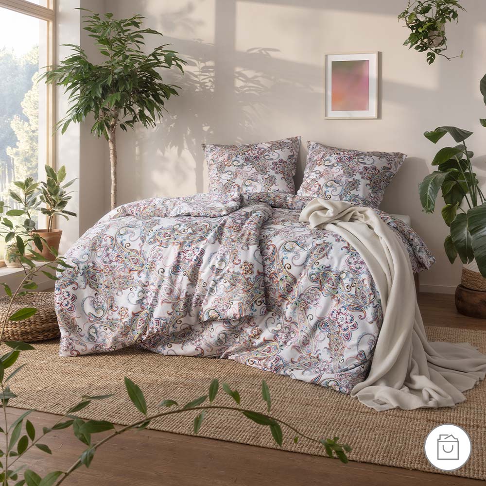 Bio-Bettwäsche mit mehrfarbigem Paisley-Muster in heller Schlafzimmerumgebung.