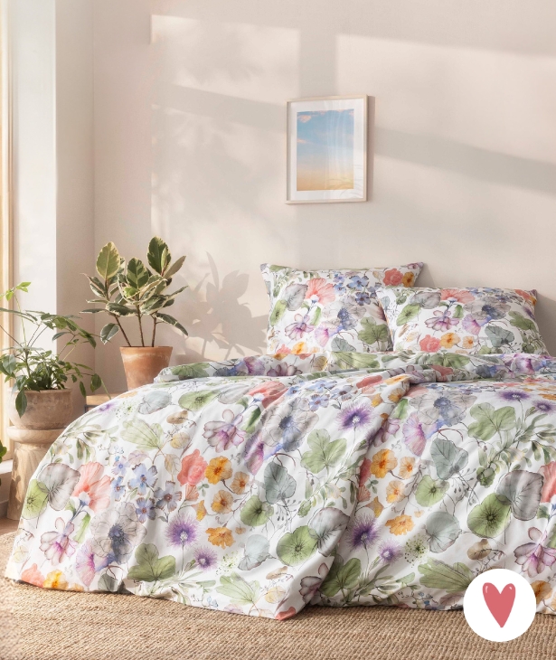 Bettwäsche Jana mit floralem Muster in Grün und Lila auf weißem Grund auf Bett im Schlafzimmer