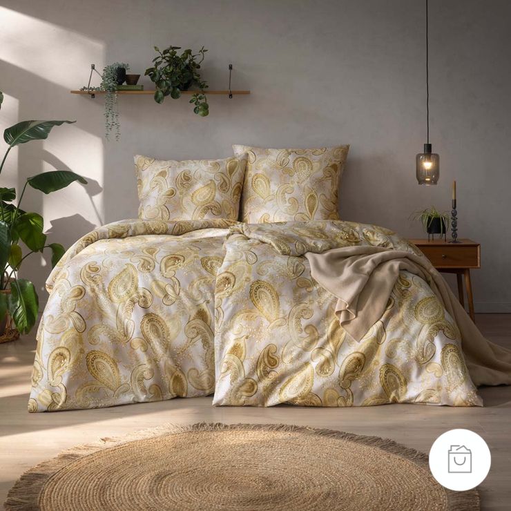 Bio-Bettwäsche Ticiana mit elegantem Paisley-Muster in Gold- und Beigetönen auf hellem Grund auf Bett im stilvollen Schlafzimmer