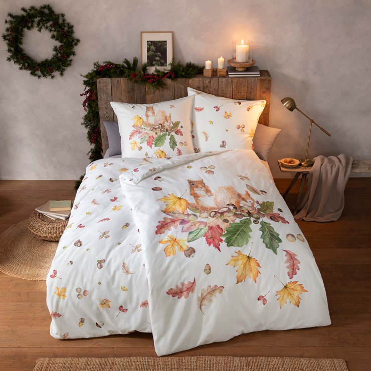Wende-Bettwäsche Squirrel mit Eichhörnchen Motiv auf der einen Seite und Herbst-Blättern in Braun und Orange auf weißem Grund auf der anderen Seite auf Bett im Schlafzimmer