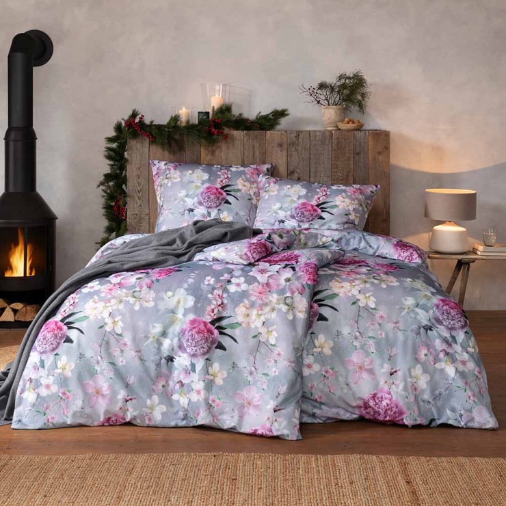 Bettwäsche Romantica mit floralem Rosenmuster in Rosa und Weiß auf grauem Grund auf Bett im Schlafzimmer