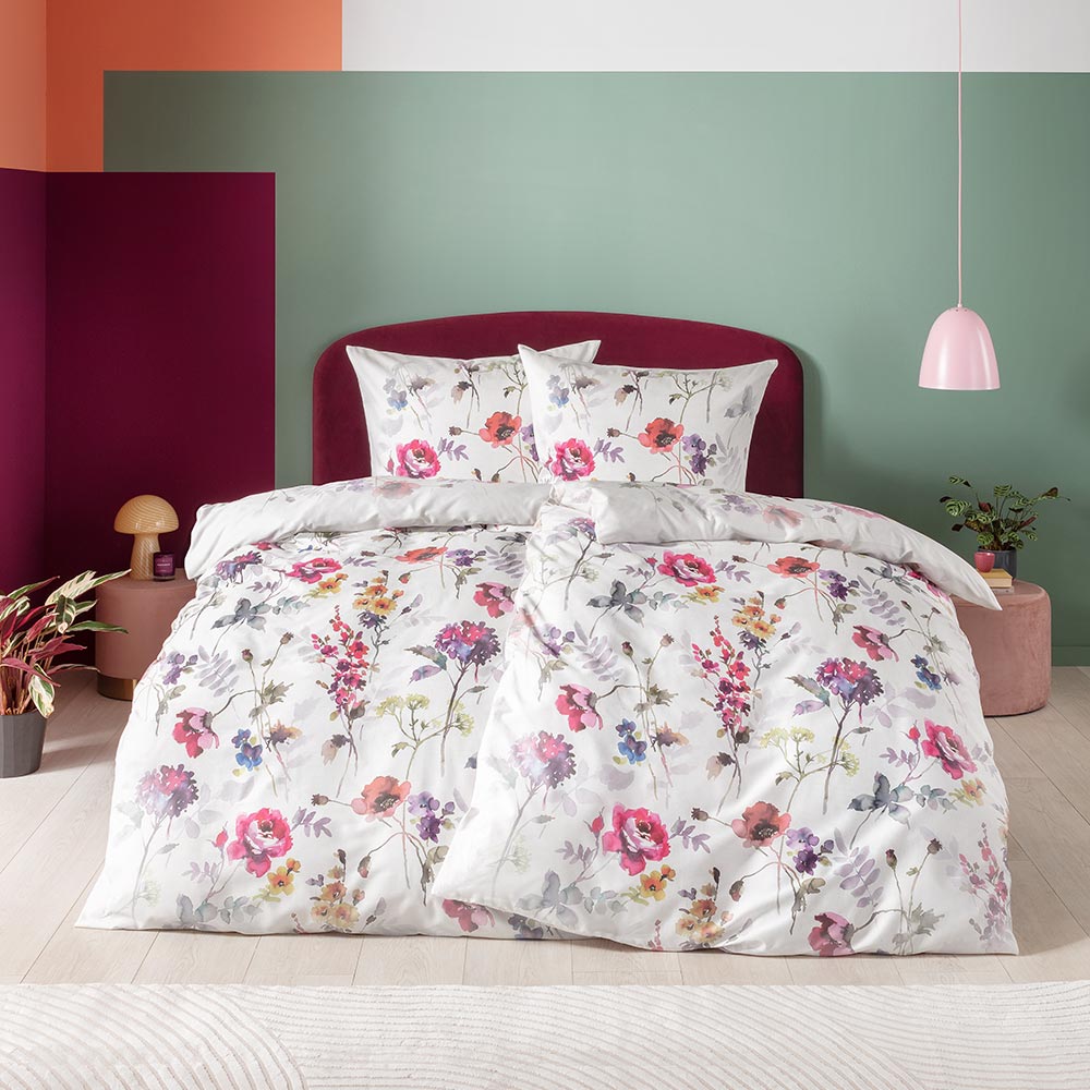Bettwäsche Hailey mit floralem Muster in Rosa und Grün auf weißem Grund auf Bett im Schlafzimmer