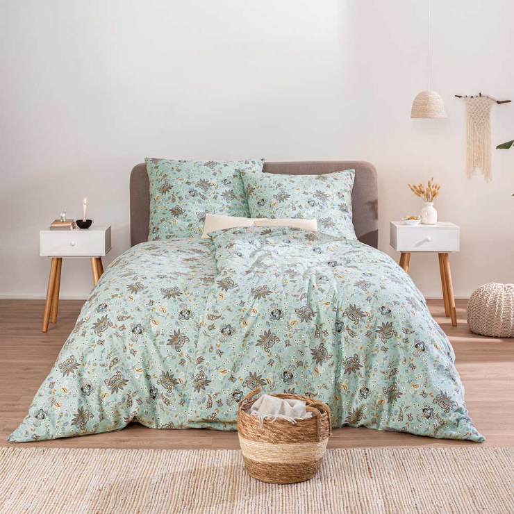 Bettwäsche Novara mit feinem Paisley-Muster aus kleinen floralen Ornamenten und geschwungenen Tropfenformen in sanften Mint-, Blau- und Beigetönen auf Bett im Schlafzimmer
