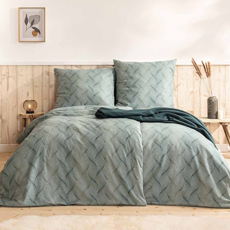 Bettwäsche Solaro mit gleichmäßigem Wellenmuster aus feinen Linien in gedämpften Grün- und Grautönen auf Bett im Schlafzimmer