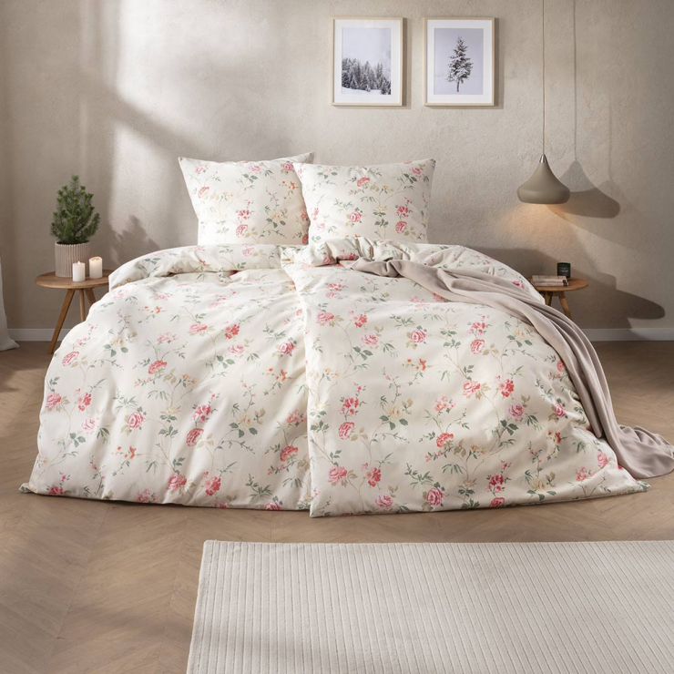 Bettwäsche Corvara mit zarten Rosenblüten und feinen Blattranken in Rosé, Grün und Creme auf hellem Grund auf Bett im Schlafzimmer