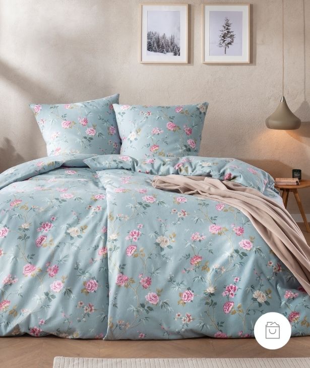 Bettwäsche Corvara mit zarten Rosenmotiven und feinen Ranken in Rosé, Creme auf sanftem blauen Grund auf Bett im Schlafzimmer