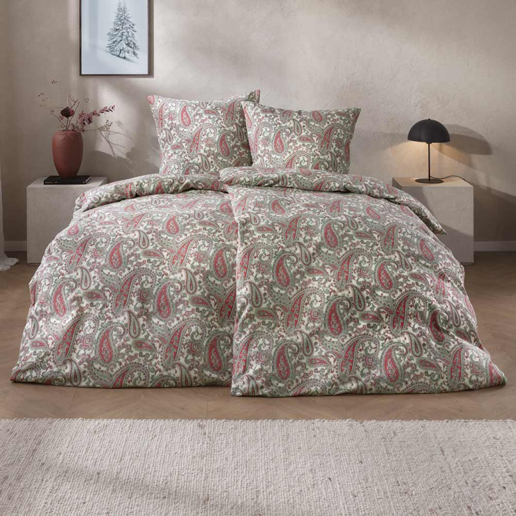 Bettwäsche Lagundo mit dichtem Paisley-Muster aus geschwungenen Ornamenten in harmonischen Grün, Rot- und Cremetönen auf hellem Grund auf Bett im Schlafzimmer
