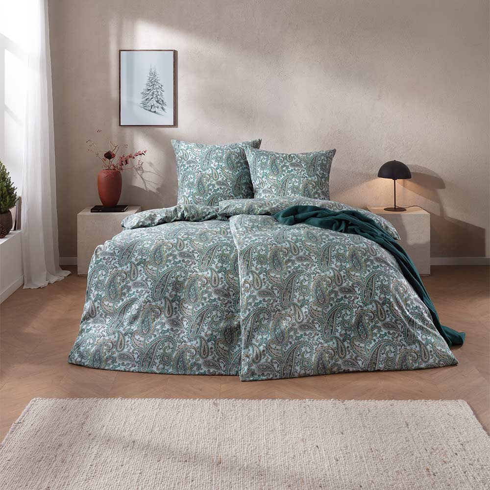 Bettwäsche Lagundo mit dichtem Paisley-Muster aus geschwungenen Ornamenten in kühlen Grün-, Blau- und Grautönen auf hellem Grund auf Bett im Schlafzimmer