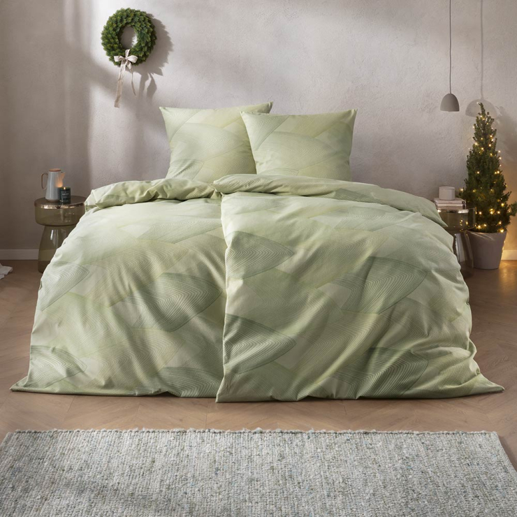 Bettwäsche Bolzano mit überlagernden Rautenformen und feinem Linienverlauf in sanften Grünnuancen auf hellgrünen Grund auf Bett im Schlafzimmer