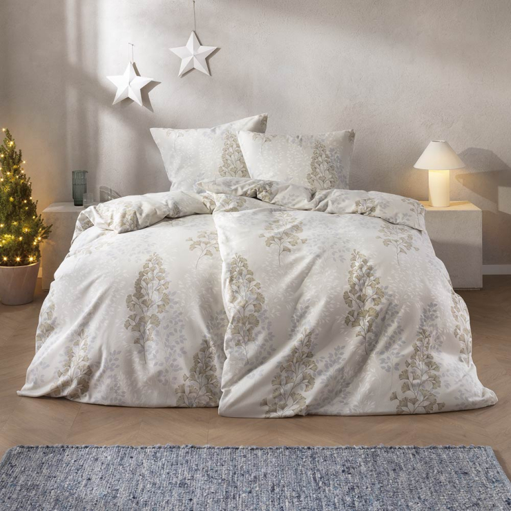 Bettwäsche Merano mit eleganten floralen Blattmotiven in feinen Gold- und Silbertönen auf hellem cremefarbenem Grund auf Bett im Schlafzimmer