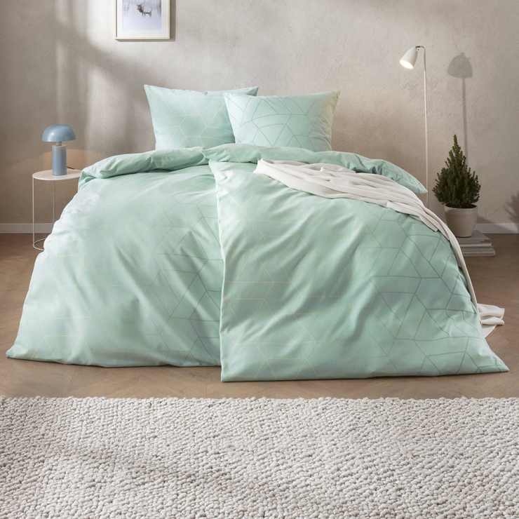 Bettwäsche Andriano mit feinem geometrischem Dreiecken in sanften Mint- und Pastellgrüntönen auf hellem Grund auf Bett im Schlafzimmer