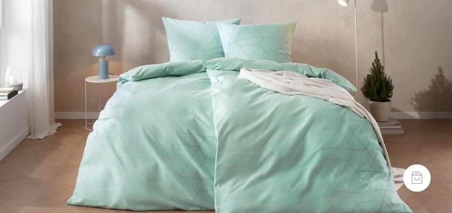 Bettwäsche Andriano mit feinem geometrischem Dreiecken in sanften Mint- und Pastellgrüntönen auf hellem Grund auf Bett im Schlafzimmer