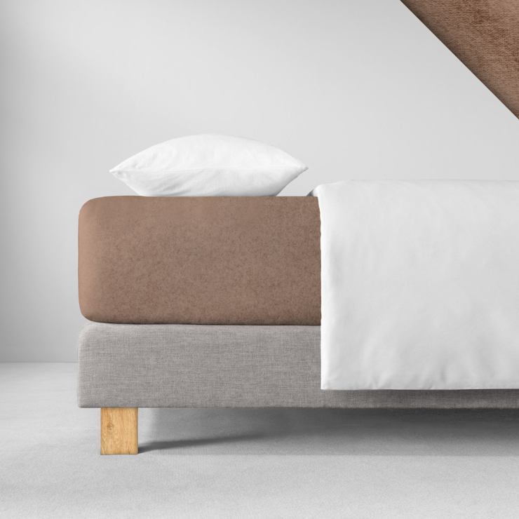 Samtiges Spannbettlaken in einem warmen, erdigen Rotbraunton aufgezogen auf Bett