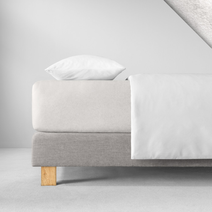 Samtiges Spannbettlaken in einem sehr hellen, fast weißen Beige aufgezogen auf Bett