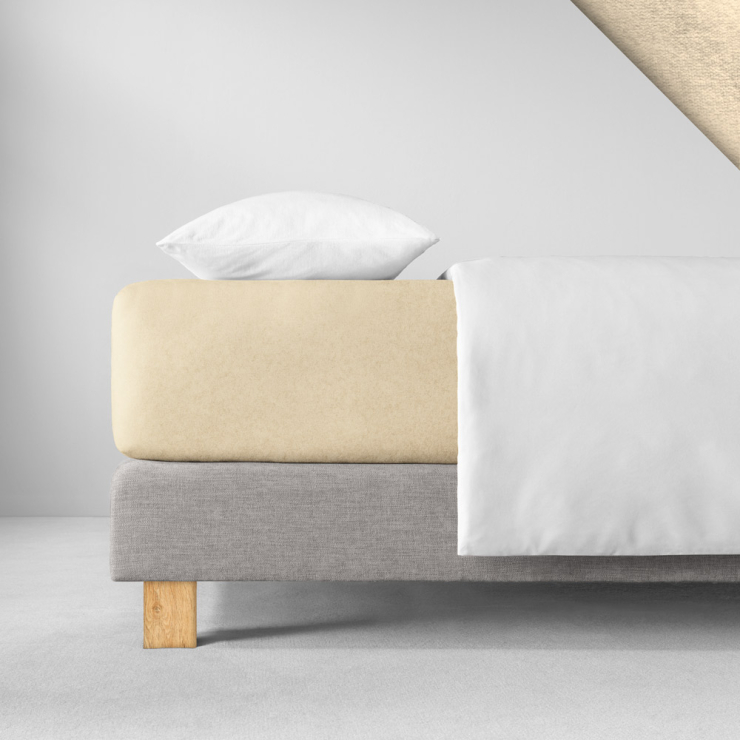 Samtiges Spannbettlaken in einem hellen, gelblich-warmen Beige aufgezogen auf Bett