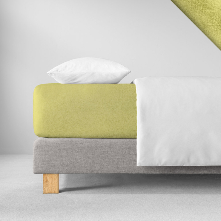 Samtiges Spannbettlaken in einem zarten, gelbgrünen Farbton aufgezogen auf Bett