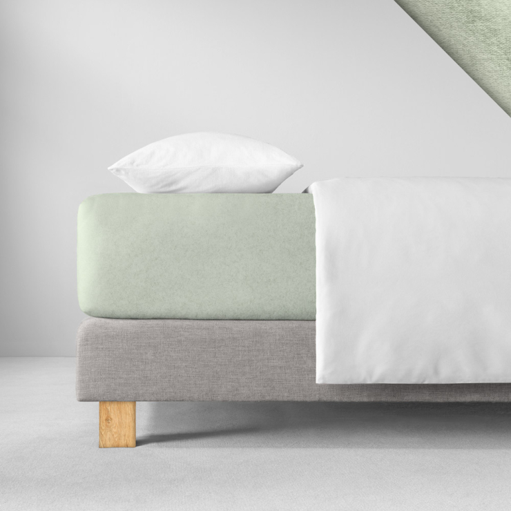 Samtiges Spannbettlaken in einem sehr hellen, pastelligen Grünton aufgezogen auf Bett