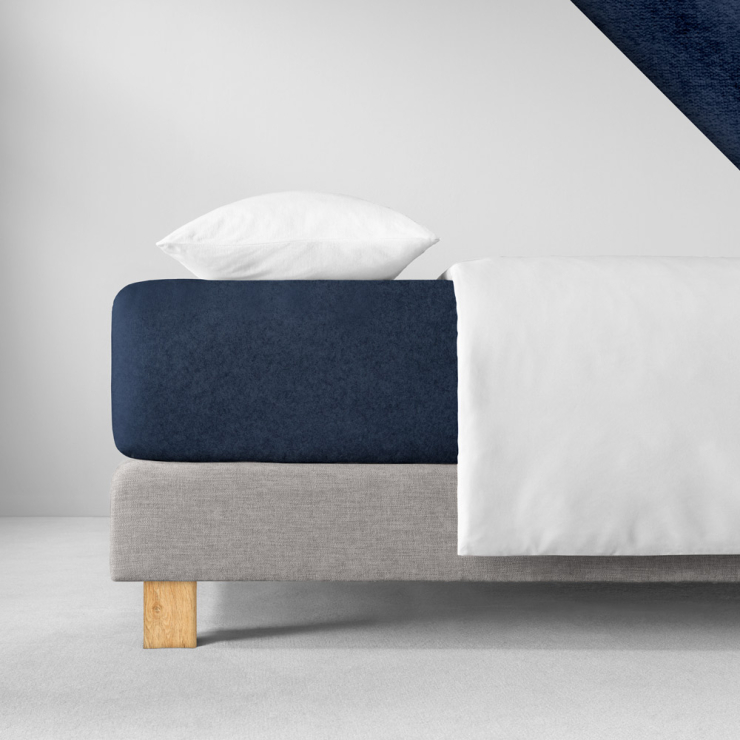 Samtiges Spannbettlaken in einem sehr dunklen, kühlen Blau aufgezogen auf Bett