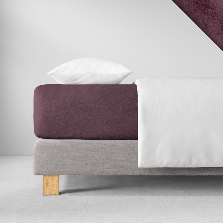 Samtiges Spannbettlaken in einem satten, dunklen beeriger Violettton aufgezogen auf Bett