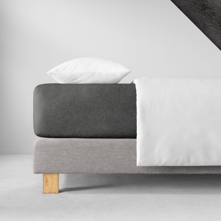 Samtiges Spannbettlaken in einem sehr  dunklen, kühlen Schwarzgrau aufgezogen auf Bett