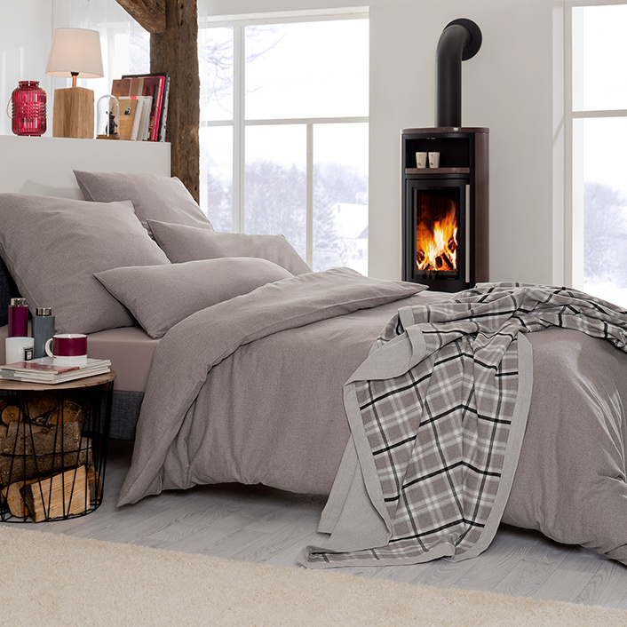 Bettwäsche Latemar in Uni-Optik mit feiner melierter Struktur in warmen Grau- und Steintönen auf Bett im Schlafzimmer