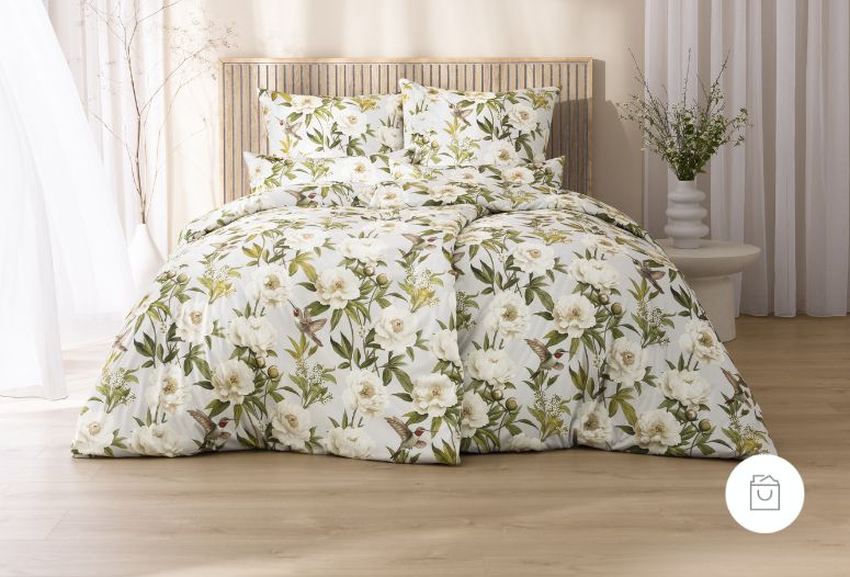 Bettwäsche Yvonne mit großen Magnolienblüten, grünen Blättern und kleinen Vögeln in Weiß-, Grün- und Naturtönen auf hellem Grund auf Bett im Schlafzimmer
