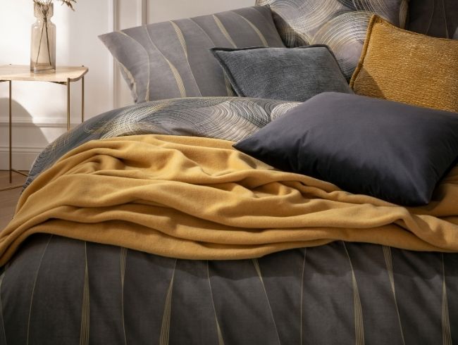 Bettwäsche Caja zusammen auf Bett kombiniert mit Wohndecke Trevi in altgold und verschiedenen Dekokissen