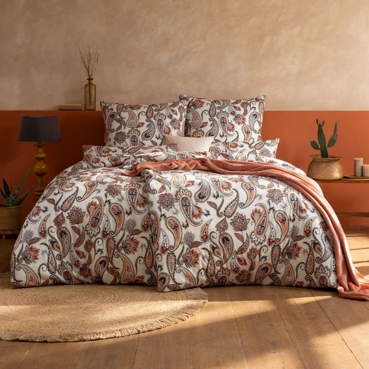 Bettwäsche Silke mit Paisley-Muster in Beige und Orange auf weißem Grund auf Bett im Schlafzimmer