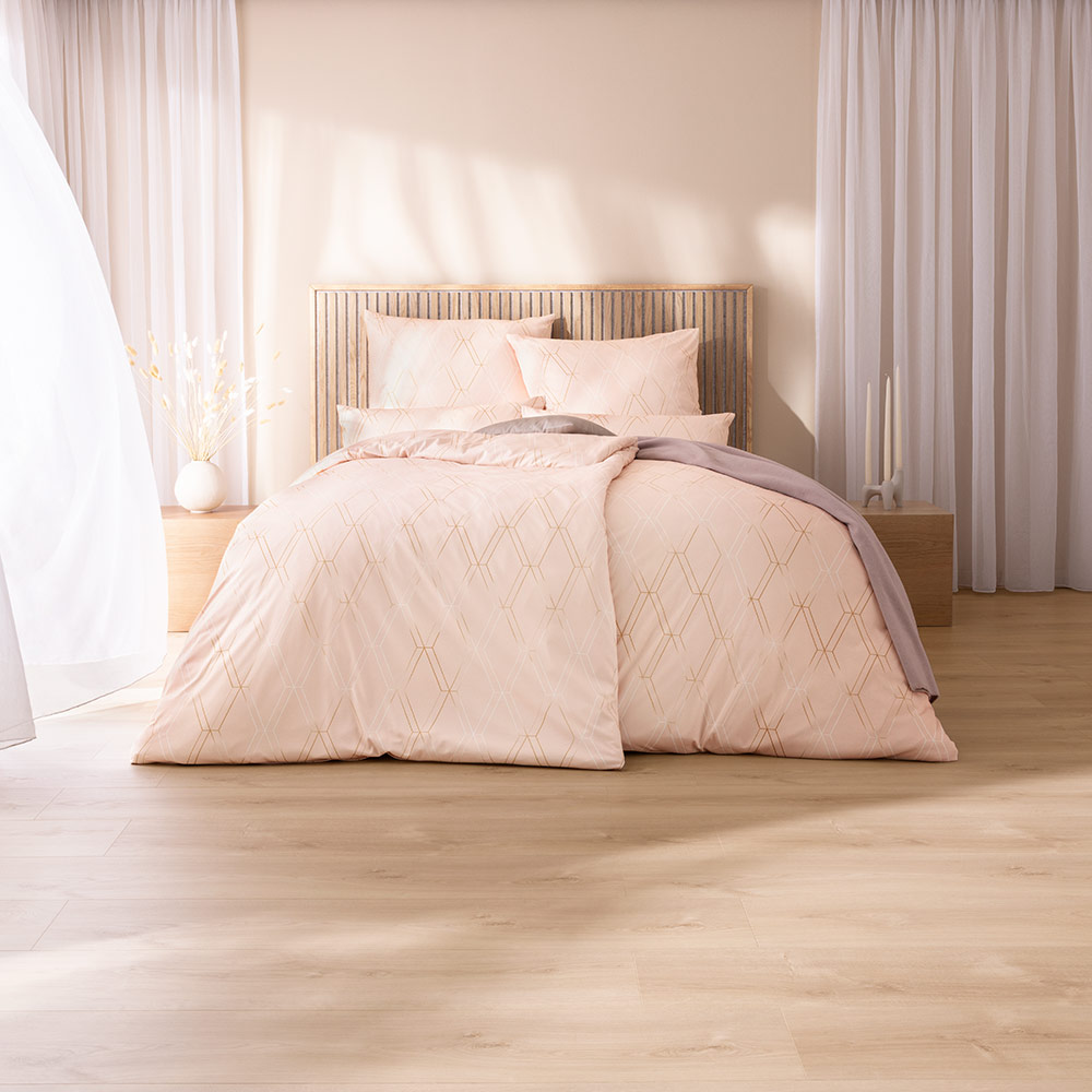 Bettwäsche Robert mit geometrischem Muster in Beige auf rosafarbenem Grund auf Bett im Schlafzimmer