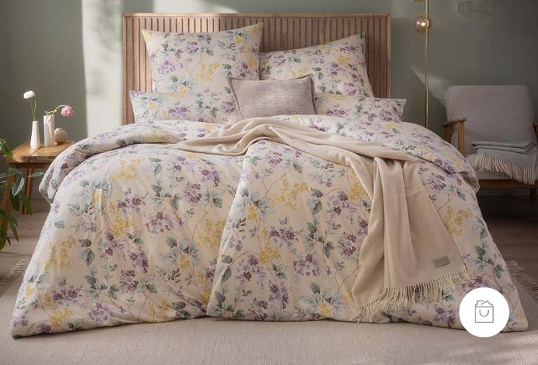 Jersey-Bettwäsche mit floralem Blütenrank-Muster in der Farbe Leinen (heller Naturton mit gelblich und lilanen Blütendesign). Demnächst verfügbar.