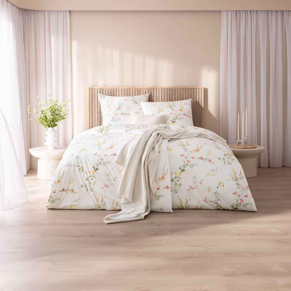 Bettwäsche Tanja mit Blumenmuster in Rosa und Grün auf weißem Grund auf Bett im Schlafzimmer