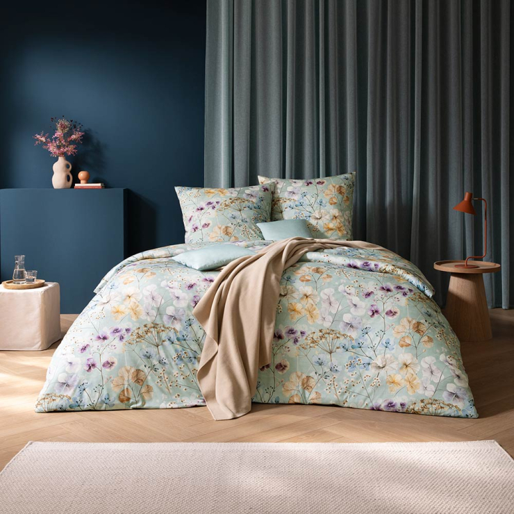 Bettwäsche Sonja mit floralem Muster in Gelb und Lila auf mintfarbenen Grund auf Bett im Schlafzimmer