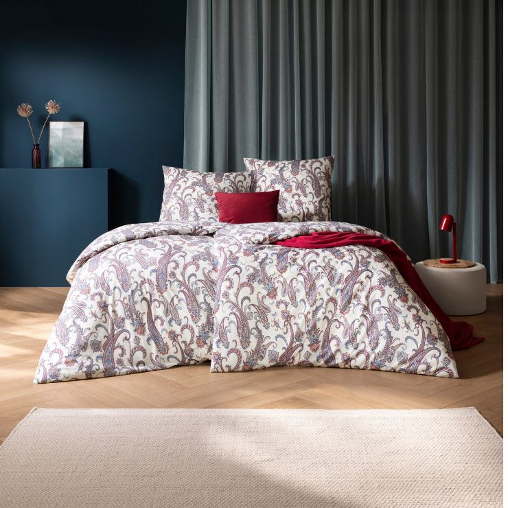 Bettwäsche Saskia mit Paisley-Muster in Lila und Blau auf weißem Grund auf Bett im Schlafzimmer