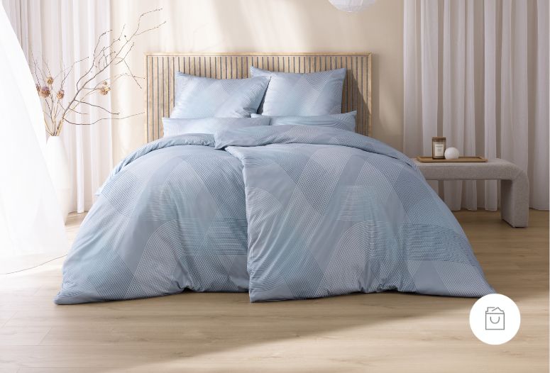 Bettwäsche Peter mit großflächigem grafischem Linienmuster aus geschwungenen Formen und feinen Punkten in kühlen Blau- und Grautönen auf Bett im Schlafzimmer