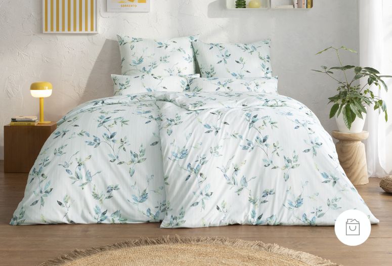 Jersey-Bettwäsche mit zartem Blättermuster in Grün und Blau auf weißem Hintergrund in hell eingerichtetem Schlafzimmer.