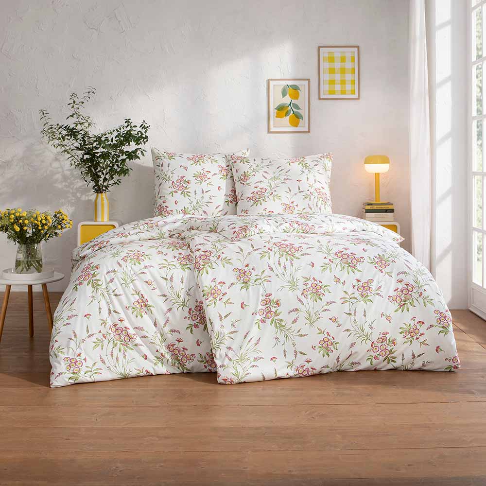 Bettwäsche Noelia mit floralem Muster in Rosa und Grün auf weißem Grund auf Bett im Schlafzimmer