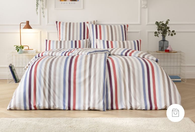 Jersey-Bettwäsche mit mehrfarbigem Streifenmuster in Rot, Blau, Grau und Beige auf Doppelbett in modernem Schlafzimmer.