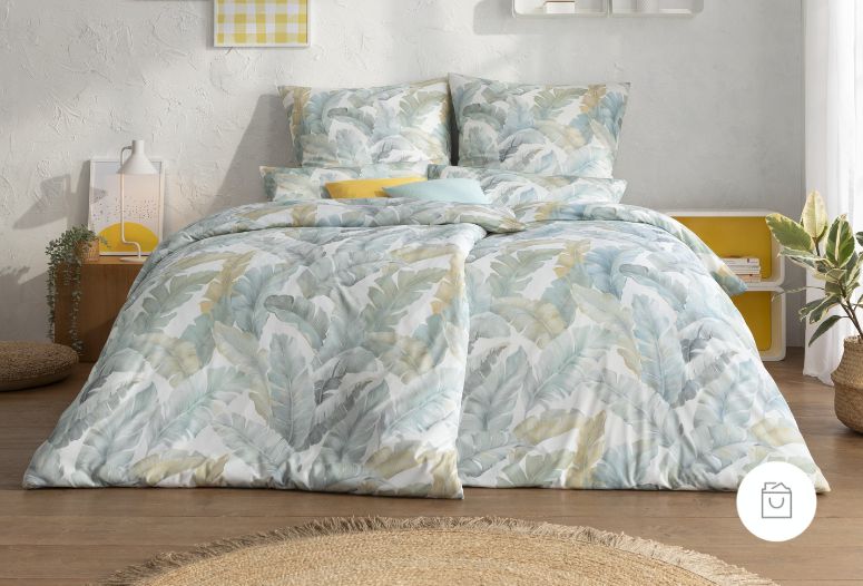 Jersey-Bettwäsche mit tropischem Blättermuster in Blau-, Grün- und Beigetönen auf Doppelbett in modernem Schlafzimmer.