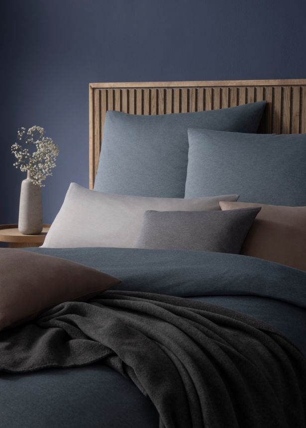 Mako-Interlock-Jersey-Bettwäsche Takoma in gedeckten Blau- und Grautönen auf Bett mit mehreren Kissen.