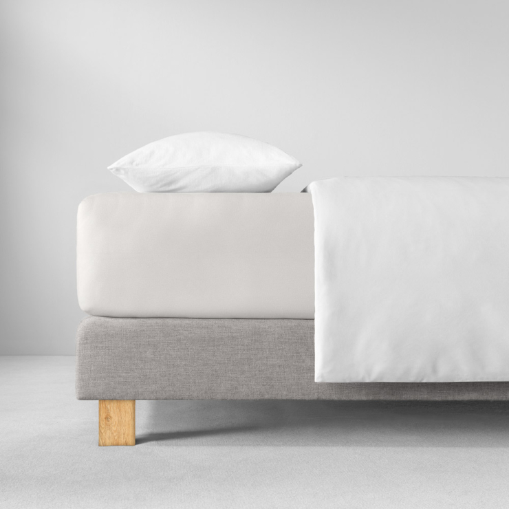 Spannbettlaken in sehr hellen, fast weissen Beigeton auf Bett aufgezogen