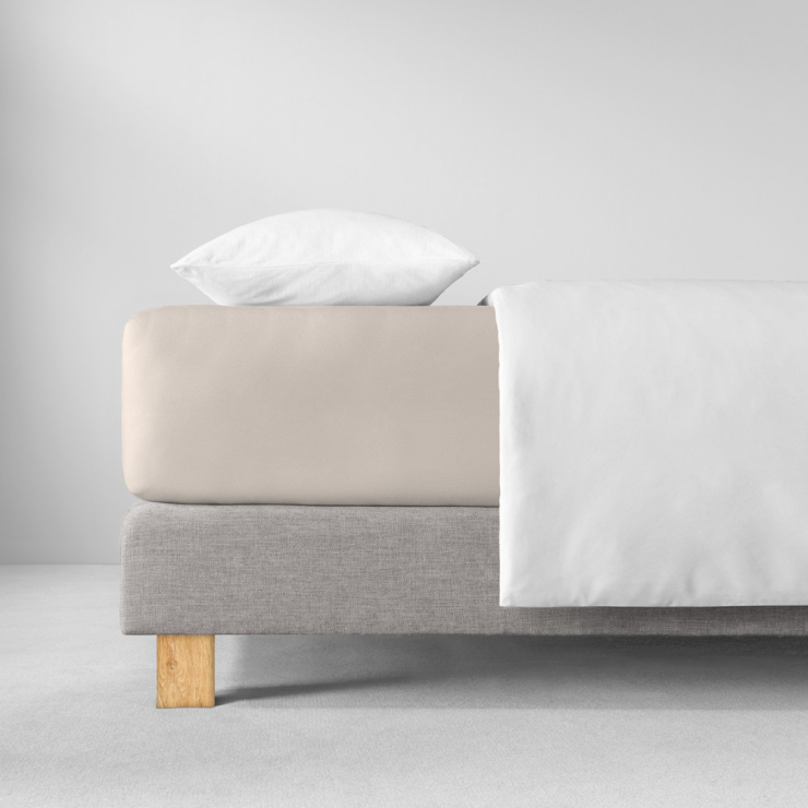 Spannbettlaken in hellen, cremigen, warmen Beigeton auf Bett aufgezogen