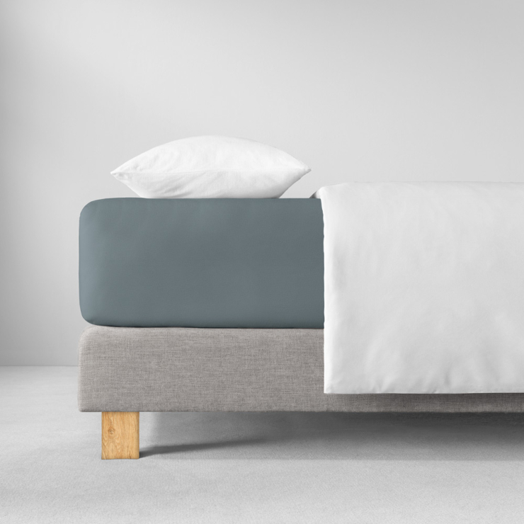 Spannbettlaken in matten, kühlen Blaugrauton auf Bett aufgezogen